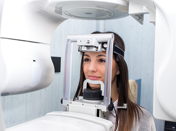 Woman undergoing dental scan in modern imaging equipment at dental clinic.