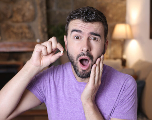Man in purple shirt displaying surprised expression with hand to face in dental office setting.