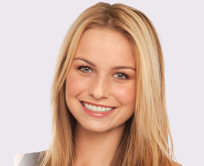 Professional headshot of smiling woman with blonde hair in dental office setting.