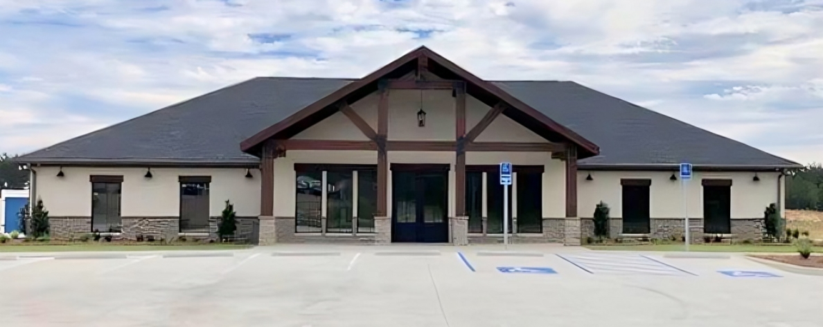 Modern dental office building with tan exterior and dark roof in rural setting.